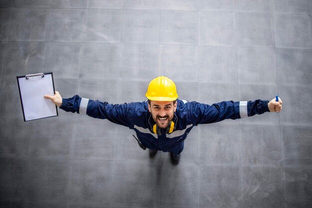 Top view of happy factory worker with raised hands celebrating promotion and success at job