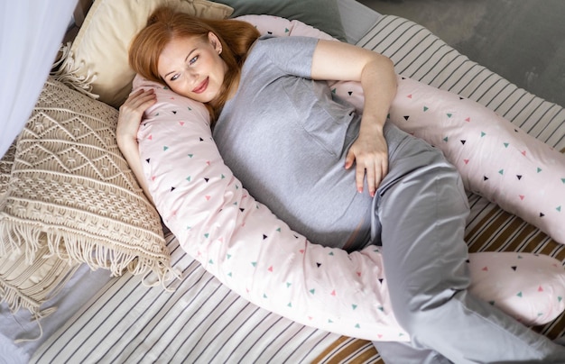Top view happy future mother lying on comfortable bed hugging pillow for pregnant relaxing