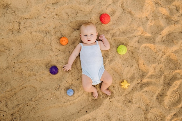 Top view of a happy little boy lying on a sandy beach