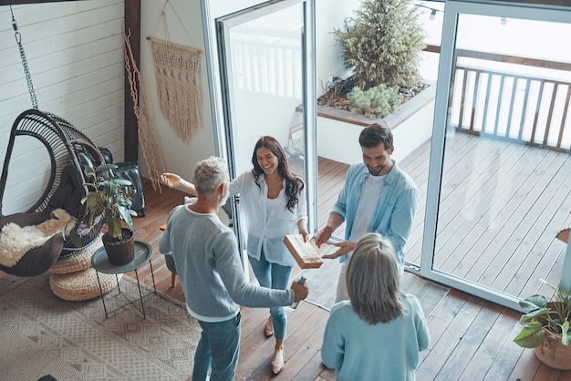 Top view of happy senior parents meeting young couple inside the house