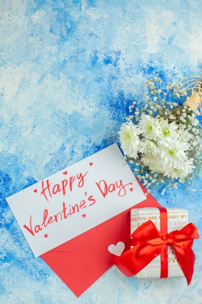 top view happy valentines day written on letter flowers red envelope gift on blue background