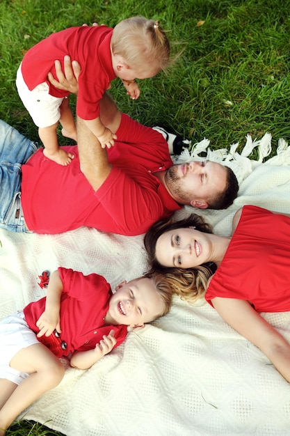 Top view of happy young family with golden retriever dog resting on grass at picnic