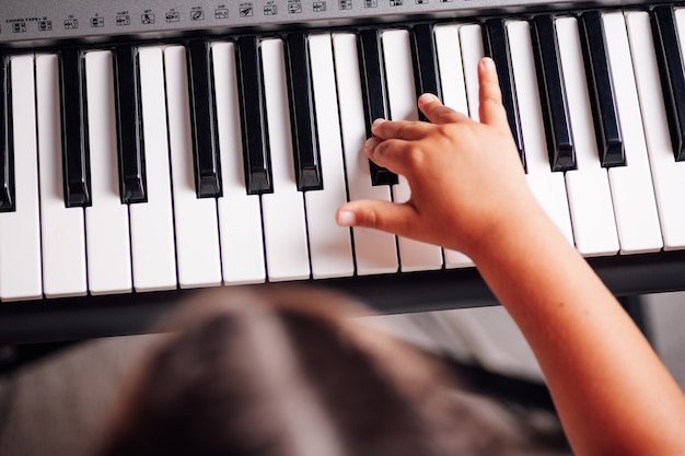 Top view of a head and a girls hand playing a tune on an electronic synthesizer