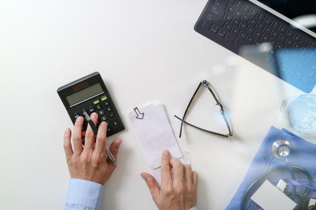 Top view of Healthcare costs and fees concept Hand smart doctor used a calculator for medical costs