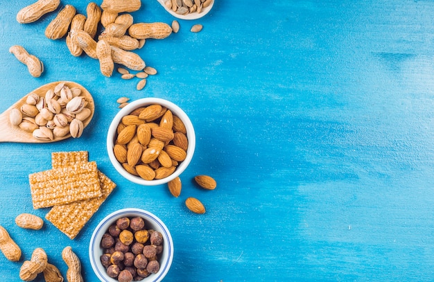 Photo top view of healthy bar made with dried fruits and seeds on blue painted background