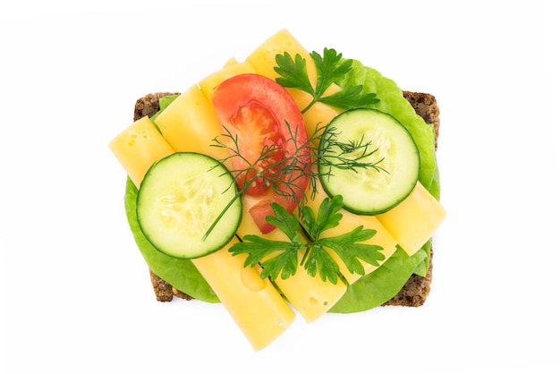 Top view of a healthy sandwich with dark full grain rye bread vegetables and cheese isolated on a white background without shadows