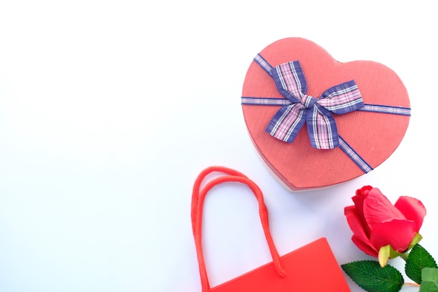 Top view of heart shape gift box and rose flower on white