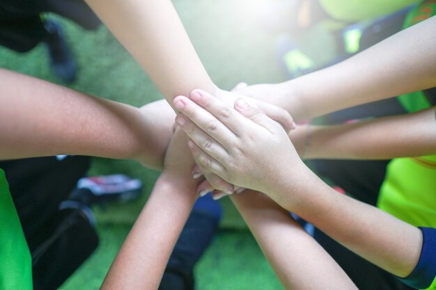 La vista superiore di alto cinque bambini passa il gesto nella squadra di football americano minore