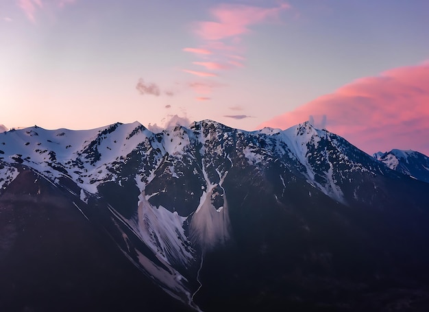 Top view of high mountains with snow caps on the peaks in nature against a pink beautiful sky