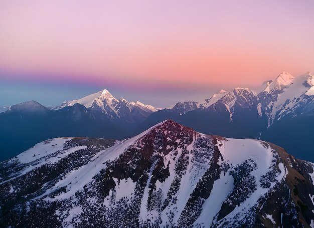 Top view of high mountains with snow caps on the peaks in nature against a pink beautiful sky