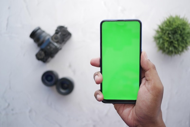 Top view of holding smart phone with green screen and camera on background