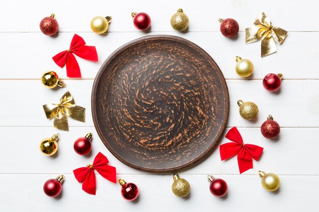 Top view of holiday dinner on wooden background Plate baubles and bows Christmas Eve concept