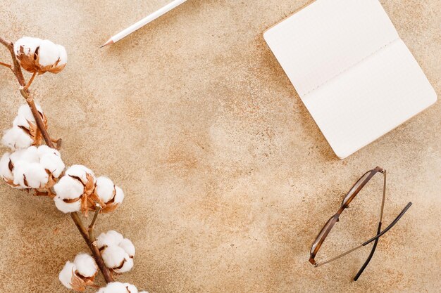 Top view on a home workspace with white open notebook pencil glasses and cotton Copy space flat lay