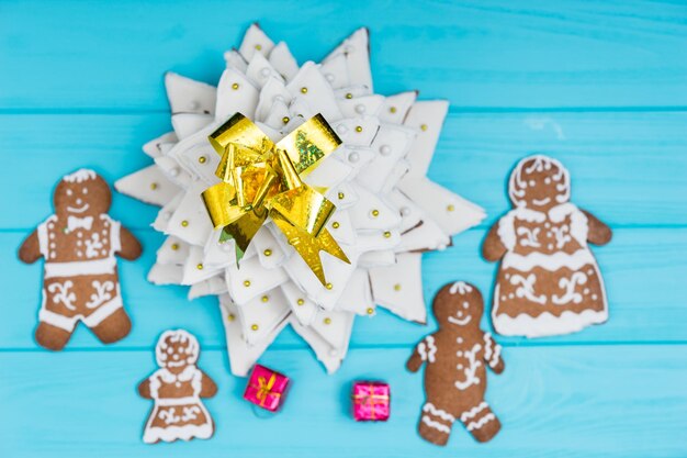 Vista dall'alto dell'albero di natale di pan di zenzero fatto in casa con una graziosa famiglia di pan di zenzero con regali sulla scrivania di legno blu. mockup per offerte stagionali e cartolina delle vacanze