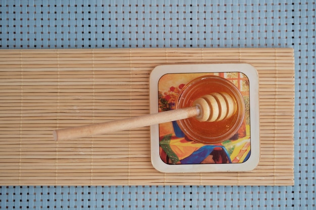 Top view of honey with a wooden honey stick dipper on the wooden table isolated on blue background.