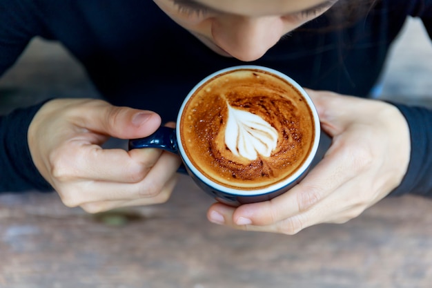 Top view of hot cappuccino coffee in the cafe, Heart shape cream coffee in blue cup.