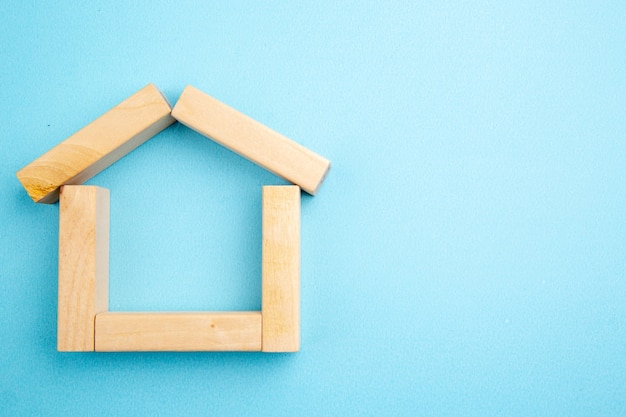 top view house shape made of wooden blocks on blue background copy place