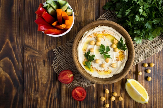 Top view of hummus in the bowl and vegetable on the rustic wooden background Closeup Copy space