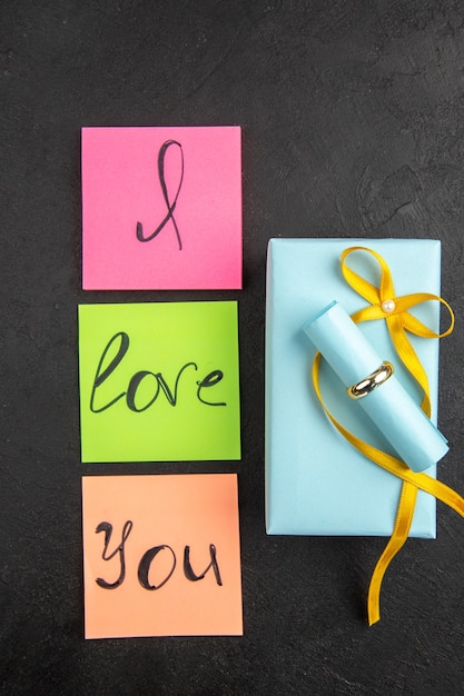 top view i love you written on colored sticky notes ring on gift on darkc background