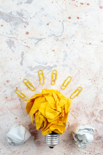 top view idea light bulb concept with crumpled yellow paper gem clips on table with free space