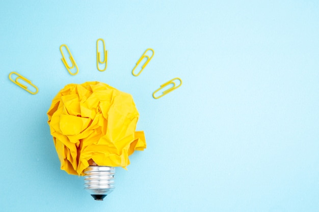 Photo top view idea light bulb concept with yellow crumpled paper and gem clips on table with free space