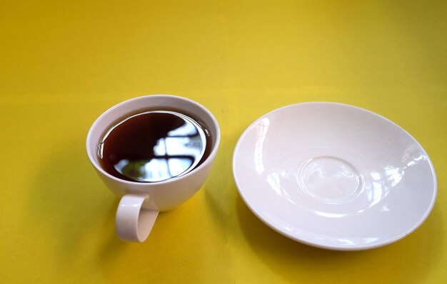 Foto immagine in alto di una tazza di caffè nera su uno sfondo giallo