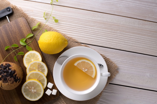 Top view image of a cup of tea with lemon on wooden table