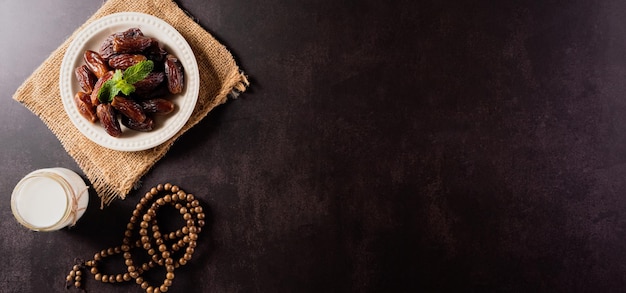 Top view image of decoration Ramadan Kareem dates fruit aladdin lamp and rosary beads on dark stone background Flat lay with copy space