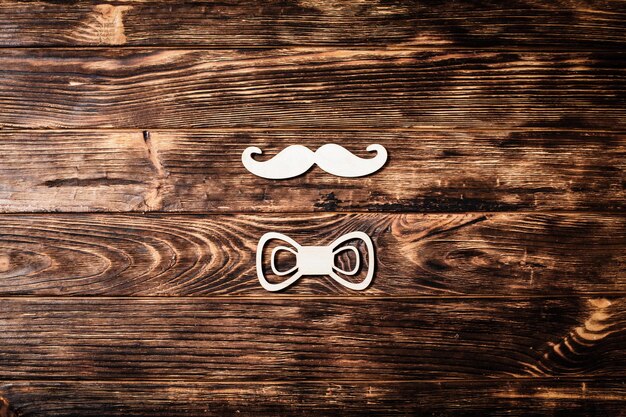 Top view image of fathers day composition with wooden mustache, bow tie forming man concept on wooden background