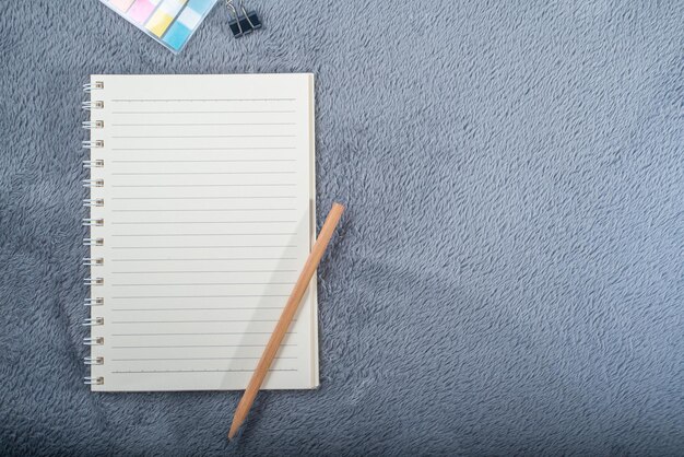 Top view image of notebook with pencil colorful mini paper note and paper clip on gray carpet