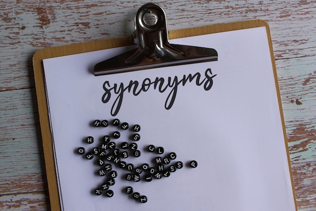 Top view image of paper clipboard with text synonyms and alphabet beads