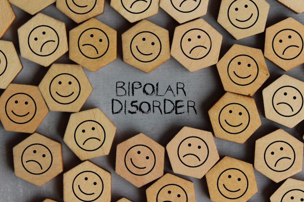 BIPOLAR DISORDER 의료 및 건강 관리 개념이 있는 미소와 슬픈 아이콘의 상위 뷰 이미지