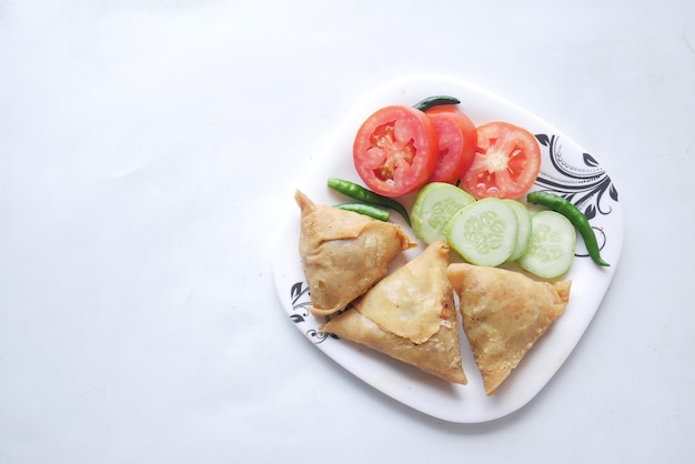 Top view of indian samosa and tomato on a plate