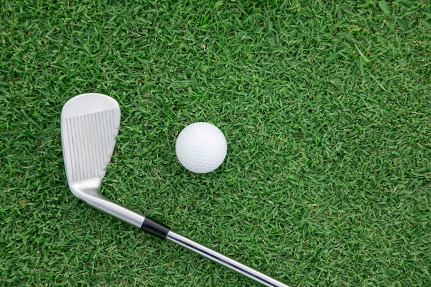 Top view of iron golf club and golf ball on the green grass