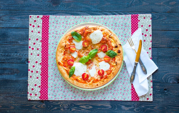 Top view of italian classic pizza margherita over a wooden table with toppings