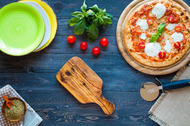 Top view of italian classic pizza margherita over a wooden table with toppings