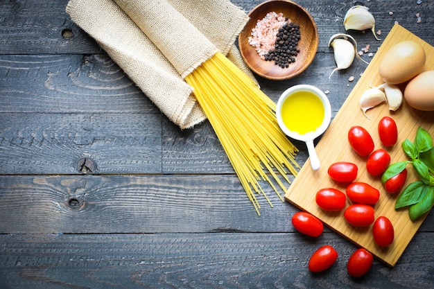 Vista dall'alto di ingredienti italiani per pomodoro e spaghetti basilici.