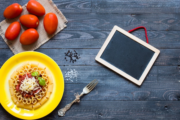 Top view of Italian pasta rigatoni with bolognese sauce, on a rustic wooden background