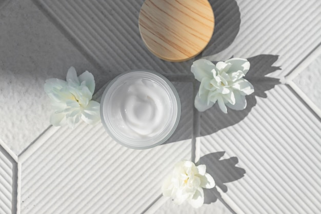 Photo top view of jar with face cream and white jasmine flowers on a concrete background place for text natural organic cosmetics concept