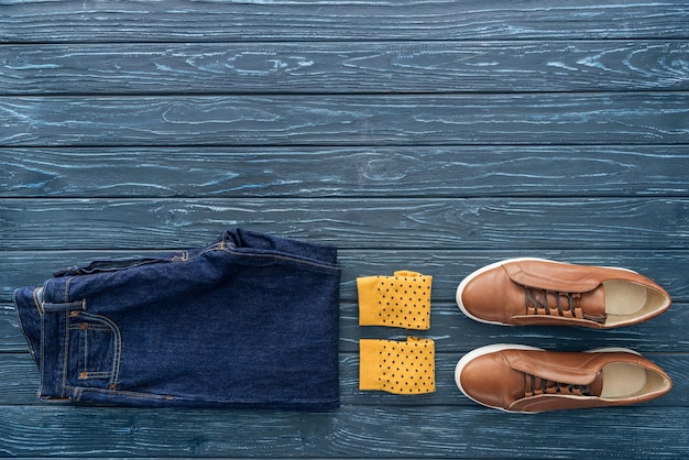 Top view of jeans yellow socks and boots on wooden background