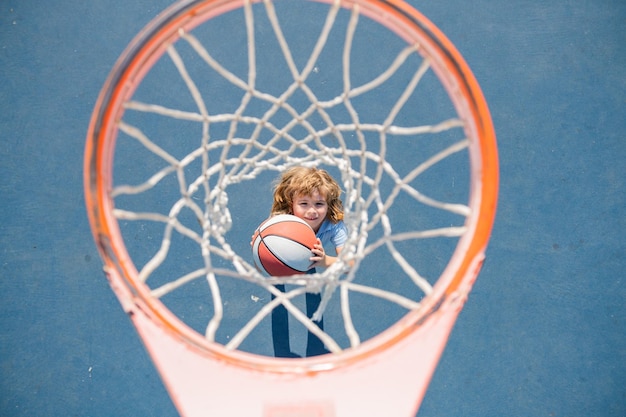 Вид сверху на ребенка, играющего в баскетбол, держащего мяч со счастливым лицом