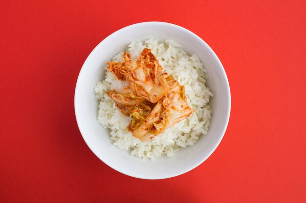 Top view of kimchi and rice in the white plate on the red