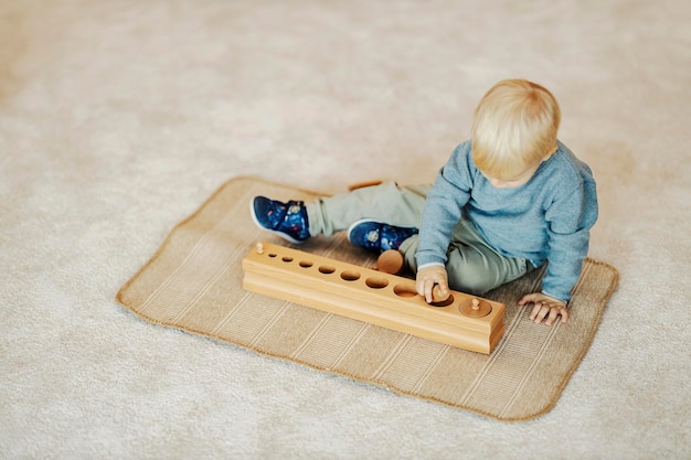 Foto vista dall'alto di un bambino dell'asilo che impara le forme attraverso il gioco con il giocattolo montessori in legno