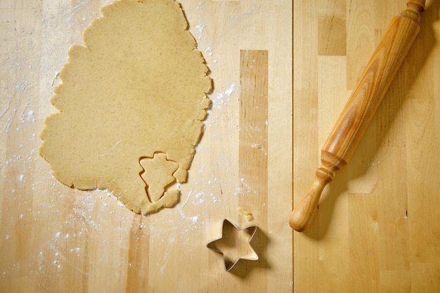 Top view of kitchen table with rolled out cookie dough cutter and rolling pin