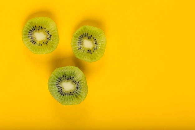 Foto vista dall'alto di fette di kiwi su sfondo giallo. cibo sano, frutta esotica