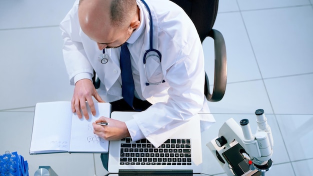 Top view. lab scientist using a laptop to save data.