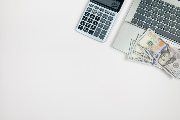 Top view of laptop and calculator with dollars on white background