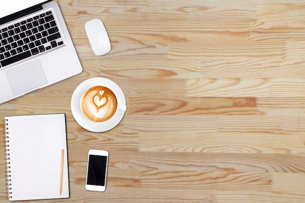 Top view laptop computer or notebookmobile phone and cup of latte art coffee on wooden table