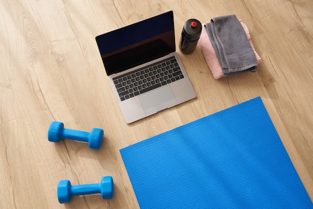 Top view of laptop  dumbbells fitness mat on the floor concept of yoga or fitness online class