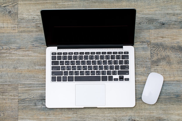 Top view of laptop notebook computer with white mouse on wooden pattern background with copy space.